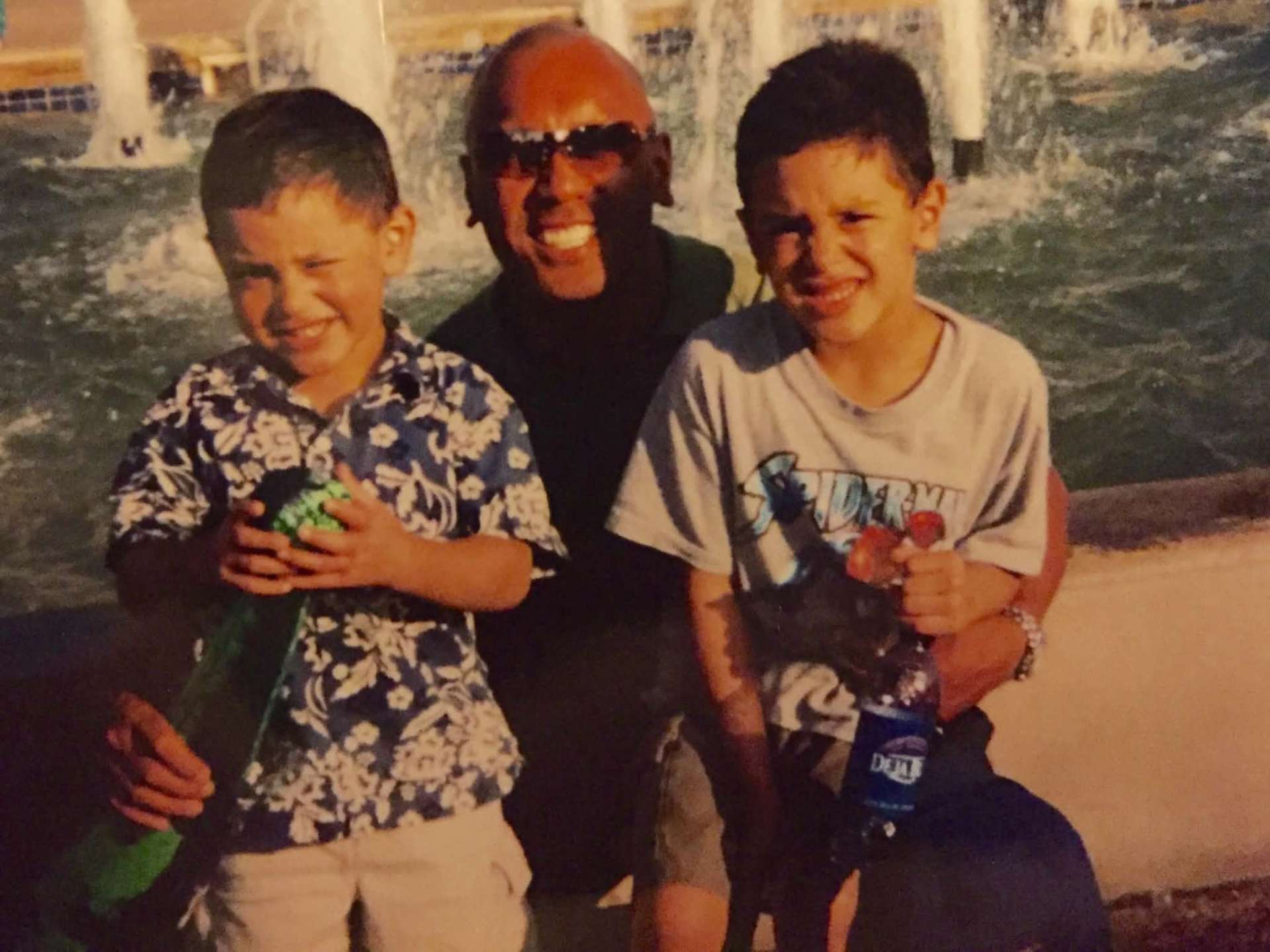 Dad and two boys smiling in front of a fountain